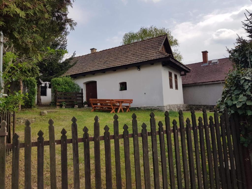 una piccola casa bianca con una recinzione di fronte di Kontyos Vendégház a Felsőtold