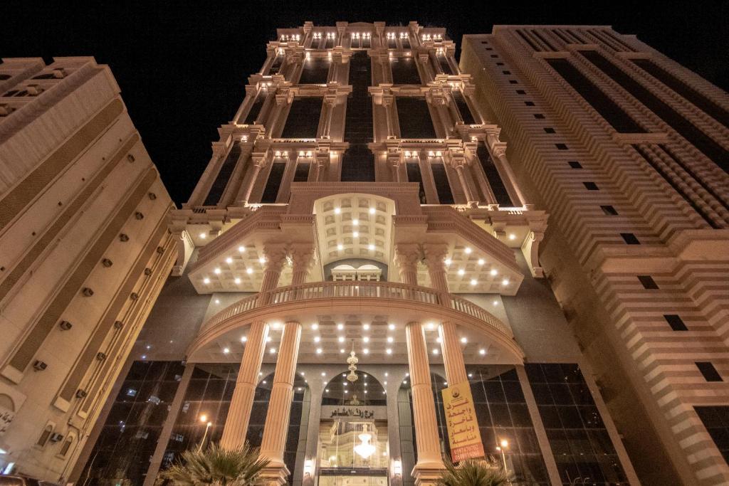 a tall building with lights on it at night at EWG Rahaf Al Mashaer Hotel in Makkah