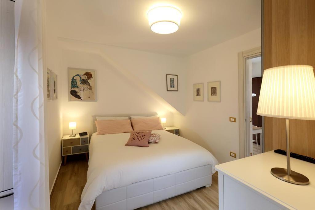 biała sypialnia z białym łóżkiem i lampką w obiekcie Casamia w mieście Mazzeo