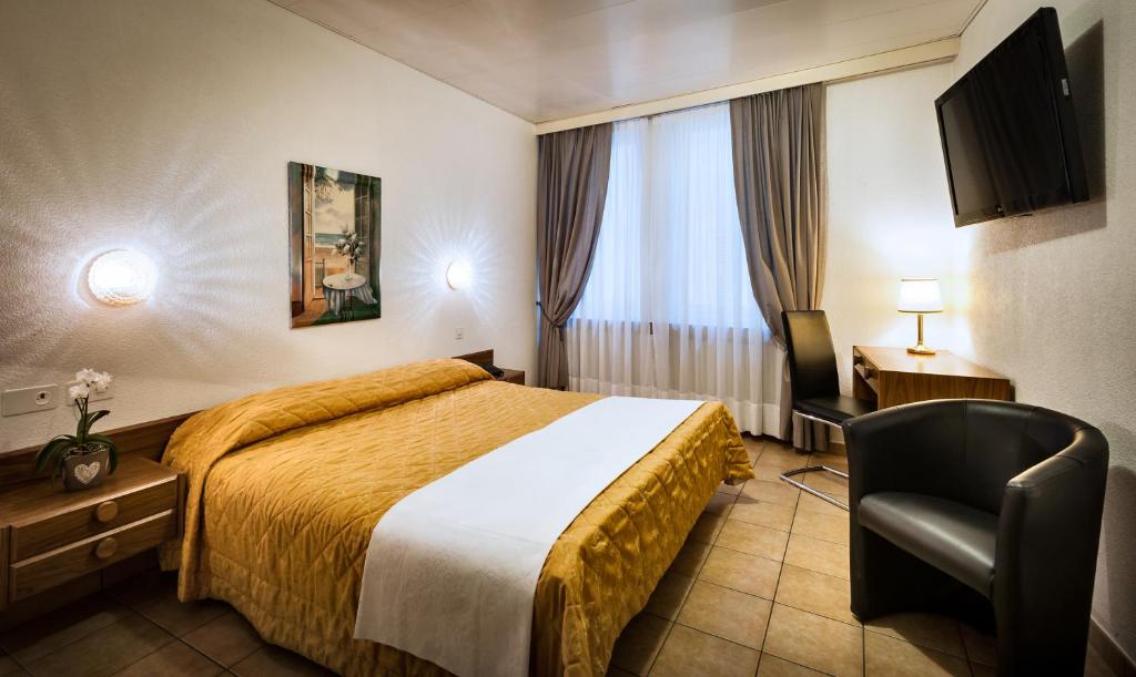 une chambre d'hôtel avec un lit et une chaise dans l'établissement Hotel dell'Angelo, à Locarno