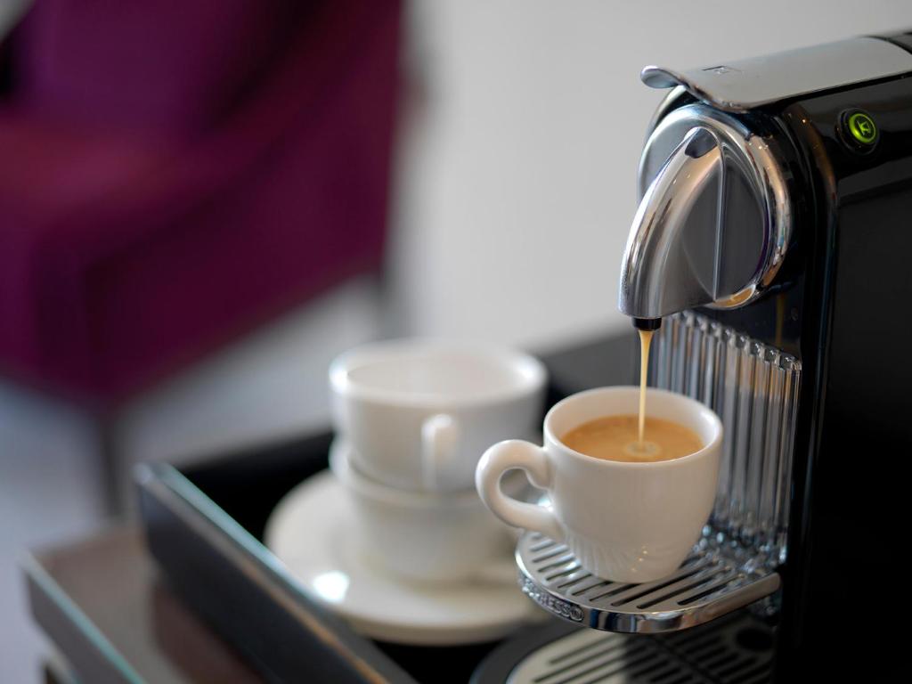 a coffee machine pouring coffee into two cups at Hotel Continental in Oslo