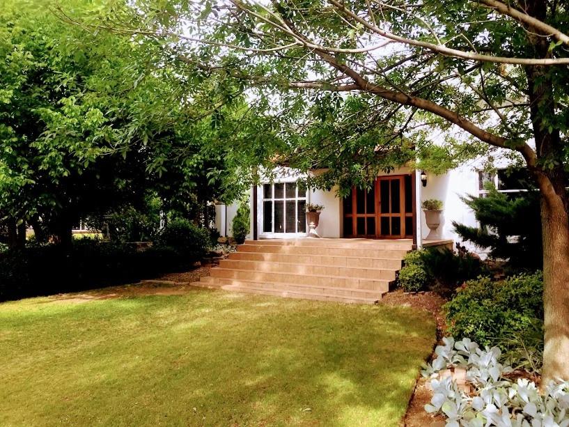 a white house with a red door and a yard at En Route Guest House in Trompsburg