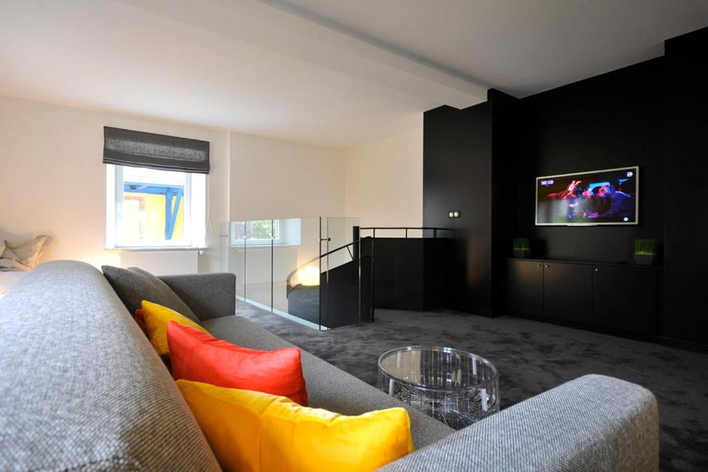 sala de estar con sofá gris y almohadas coloridas en Le Duplex de Jules, en Orbey
