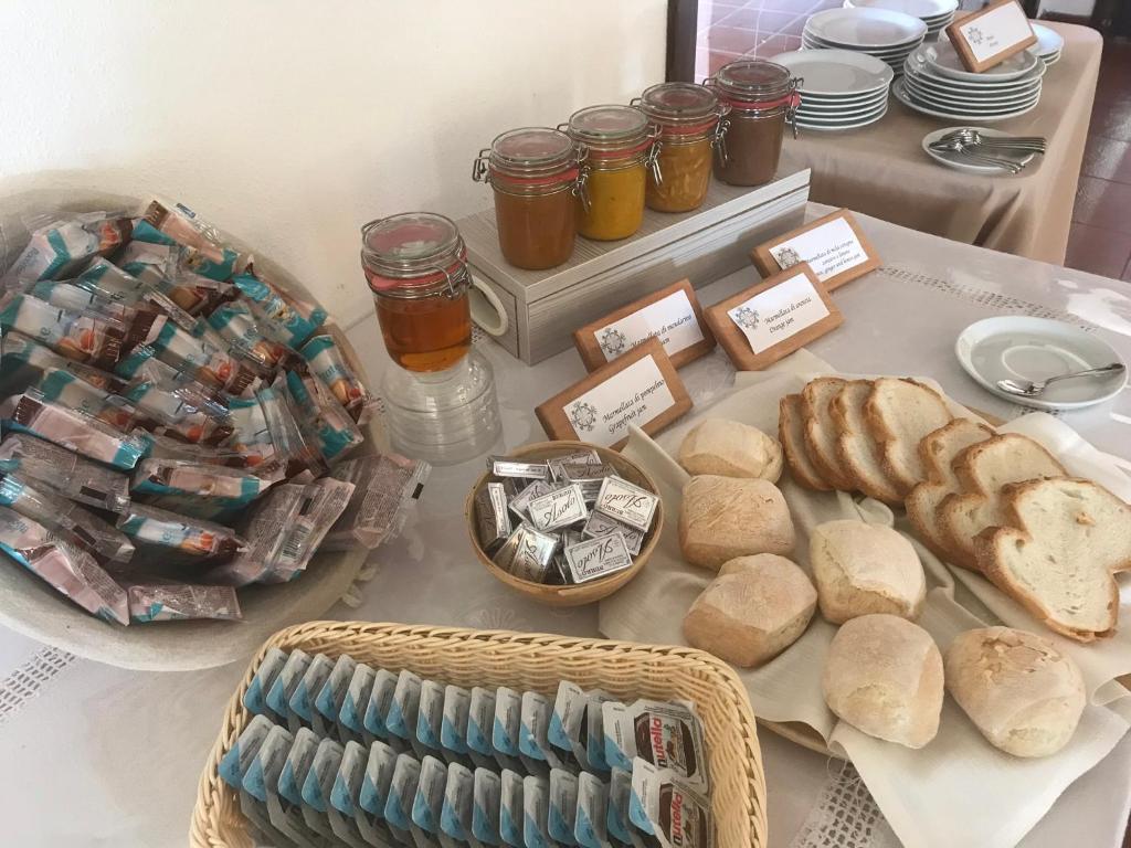 a table with bread and jars of honey and sandwiches at Hotel Spartivento in Chia