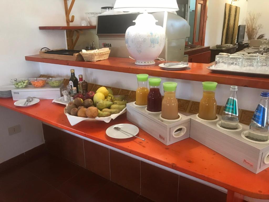 a counter with bottles of juice and a bowl of fruit at Hotel Spartivento in Chia
