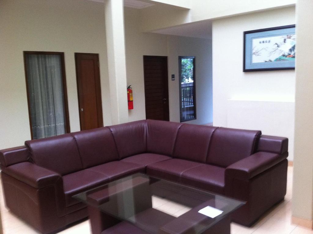 a living room with a brown leather couch and a table at Votel Viure Hotel Jogjakarta in Yogyakarta