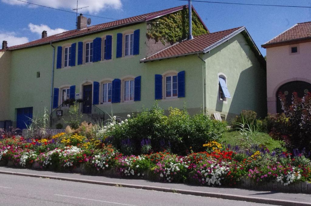 una casa con finestre blu e fiori di fronte di Chambres d'hôtes Au presbytère a Racrange
