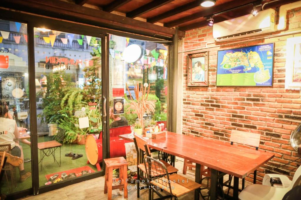 un restaurante con una mesa de madera y una pared de ladrillo en De Pumpkiin Hostel en Phra Nakhon Si Ayutthaya