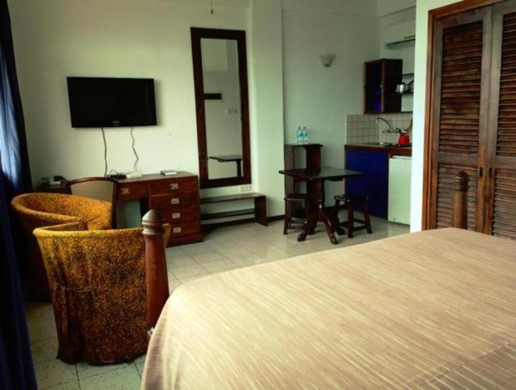 Schlafzimmer mit einem Bett, einem Schreibtisch und einem TV in der Unterkunft Slipway Studios in Daressalam