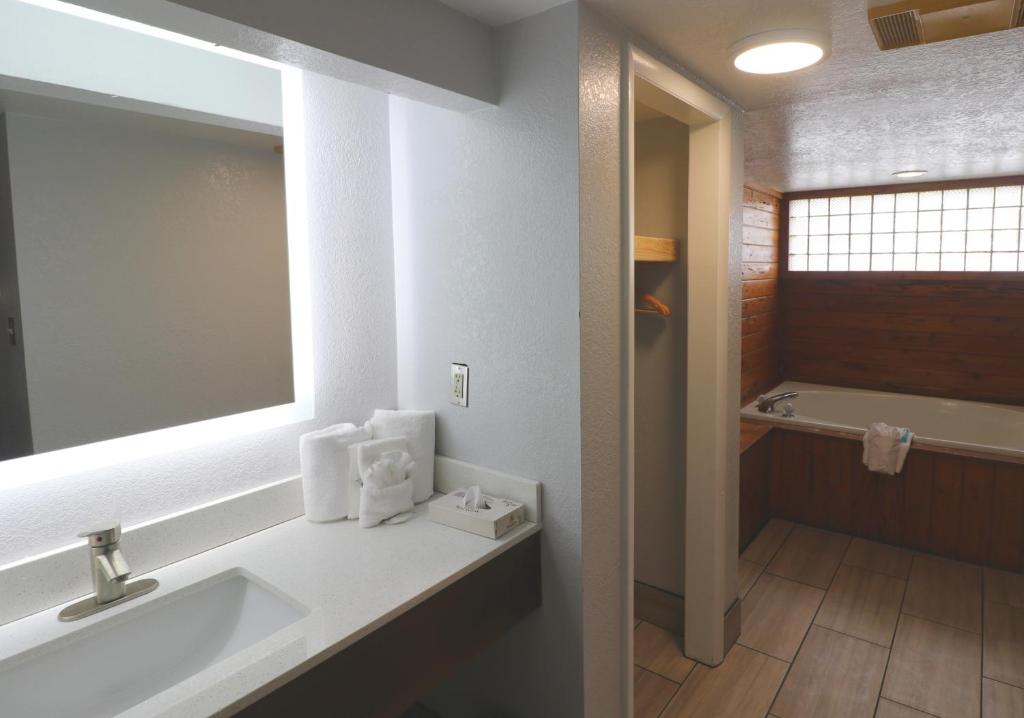 a bathroom with a sink and a mirror and a tub at Howard Johnson by Wyndham Downtown Gatlinburg in Gatlinburg