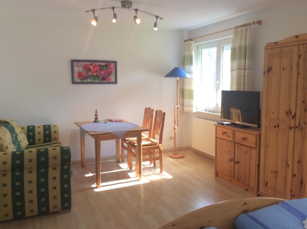 ein Wohnzimmer mit einem Tisch, Stühlen und einem TV in der Unterkunft FeWo Wende in Heringsdorf