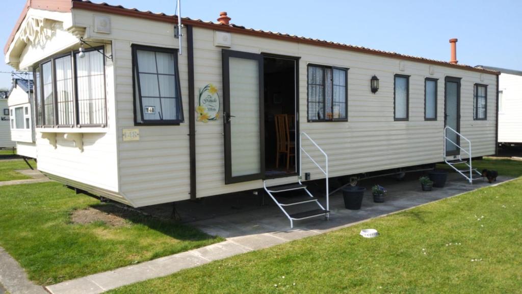 a white house with a door and a porch at H&B Caravan on Marine Holiday Park in Rhyl