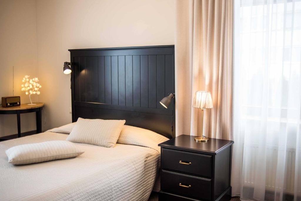 a bed with a black headboard and a lamp on a night stand at Province in Cēsis