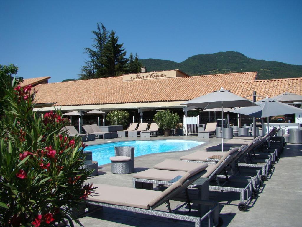 a swimming pool with lounge chairs and umbrellas at Le Mas d'Estello in Tallard