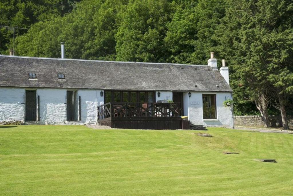 a house with a large green field in front of it at Jock Scott Cottage in Dunkeld