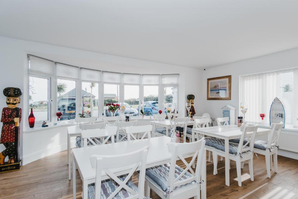 a dining room with white tables and white chairs at Elysian Fields B&B in Helston