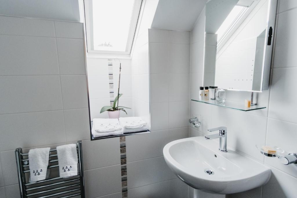 a white bathroom with a sink and a window at Elysian Fields B&B in Helston