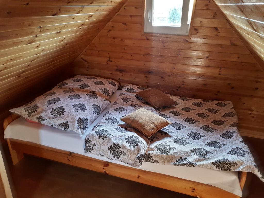 a bed in a log cabin with pillows on it at Tajek in Stegna