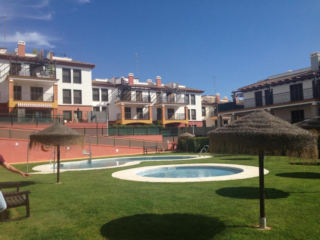 une piscine avec des parasols dans une cour avec des bâtiments dans l'établissement Costa Esuri Golf y Playa, à Ayamonte