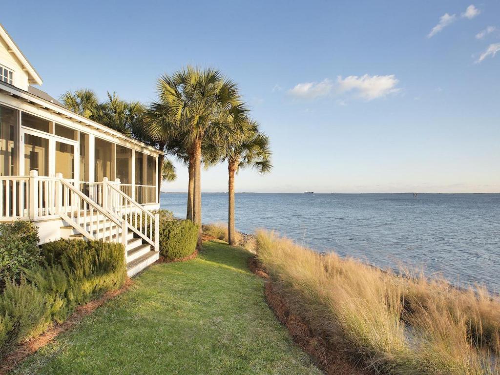 a house with palm trees next to the water at The Cottages on Charleston Harbor in Charleston