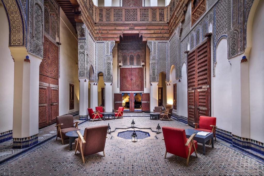 une chambre avec des chaises et des tables dans un bâtiment dans l'établissement Hotel & Spa Dar Bensouda, à Fès