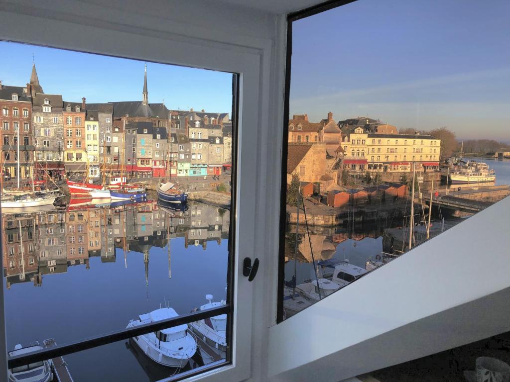 een raam met uitzicht op een haven met boten bij Lucarne Enchantée in Honfleur