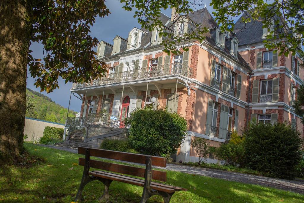 un banco del parque frente a un gran edificio en VILLA BONVOULOIR, en Bagnères-de-Bigorre