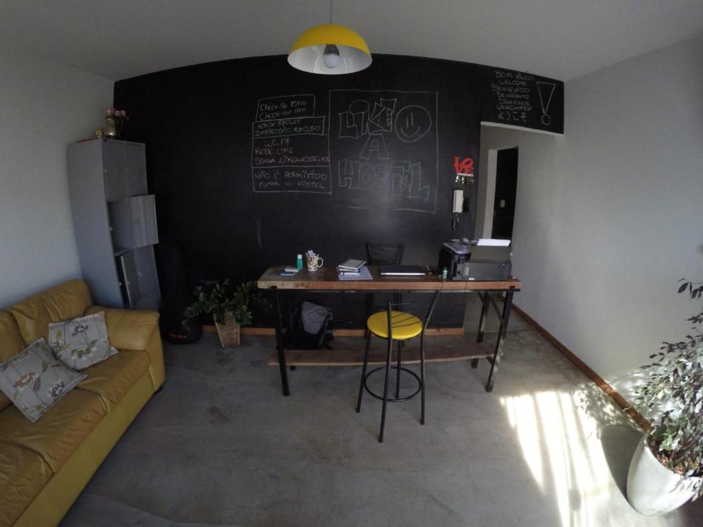 a room with a desk with a couch and a chalkboard at Like a Hostel in Poços de Caldas