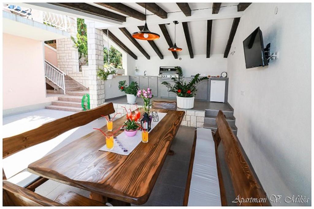 patio z drewnianym stołem i kwiatami w obiekcie Apartmani Vesna Miliša w Primošten