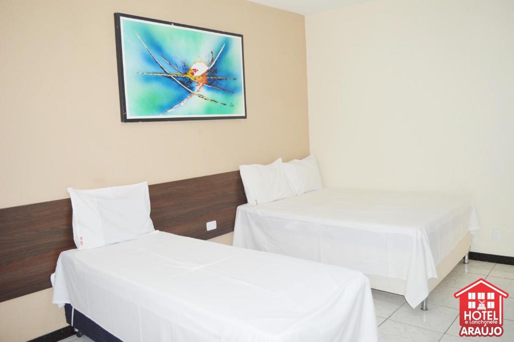 2 camas en una habitación con una foto en la pared en Hotel e Restaurante Araújo en Montes Claros