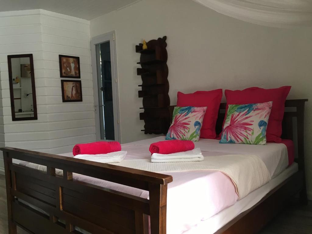 1 dormitorio con 1 cama con almohadas rojas en Studio Bleu Lagon dans résidence avec piscine, en Le Gosier