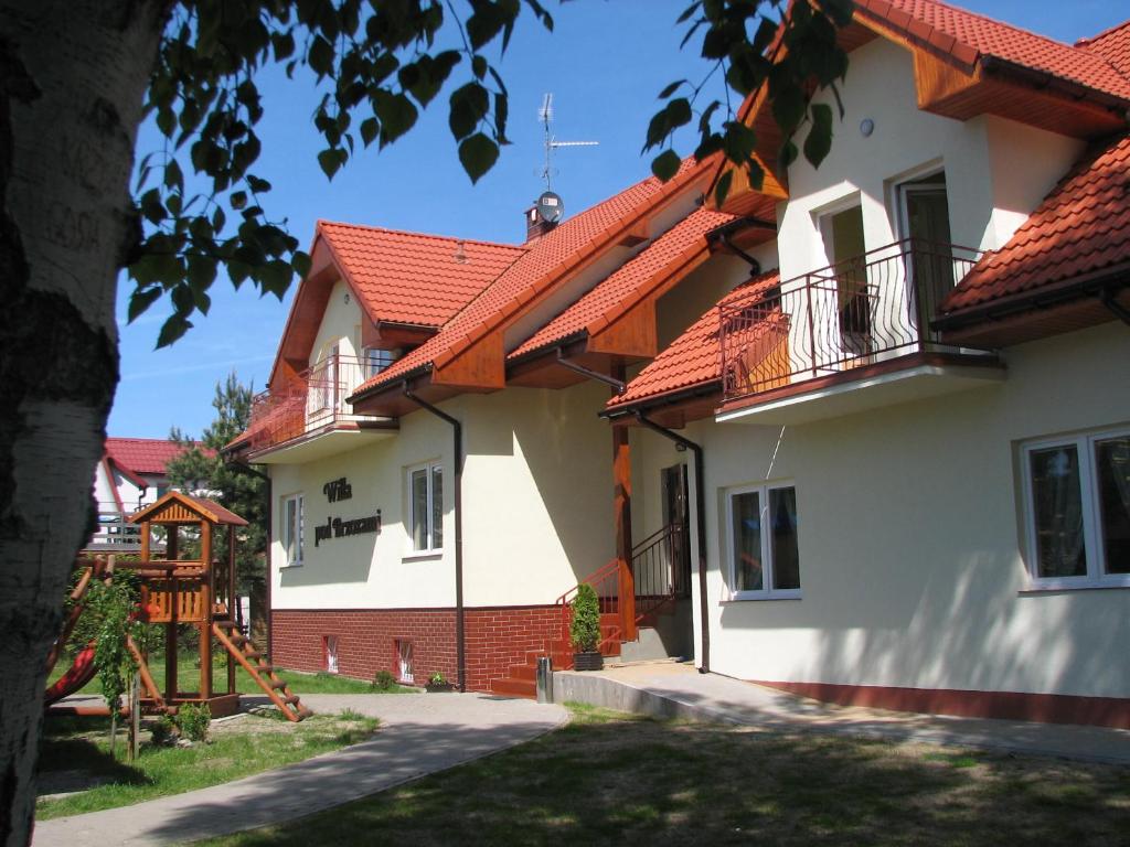 biały dom z czerwonym dachem w obiekcie Willa pod Brzozami w mieście Niechorze