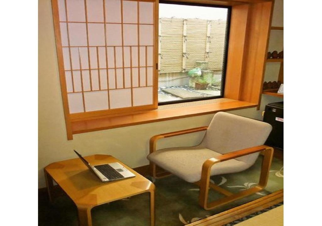 Zimmer mit einem Stuhl und einem Tisch mit einem Laptop in der Unterkunft Wakaba Ryokan / Vacation STAY 29362 in Sakata