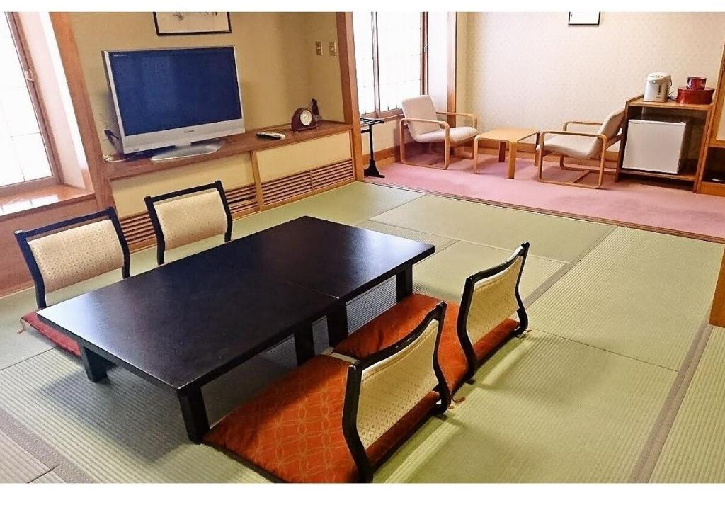 um quarto com uma mesa e cadeiras e uma televisão em Wakaba Ryokan / Vacation STAY 29376 em Sakata