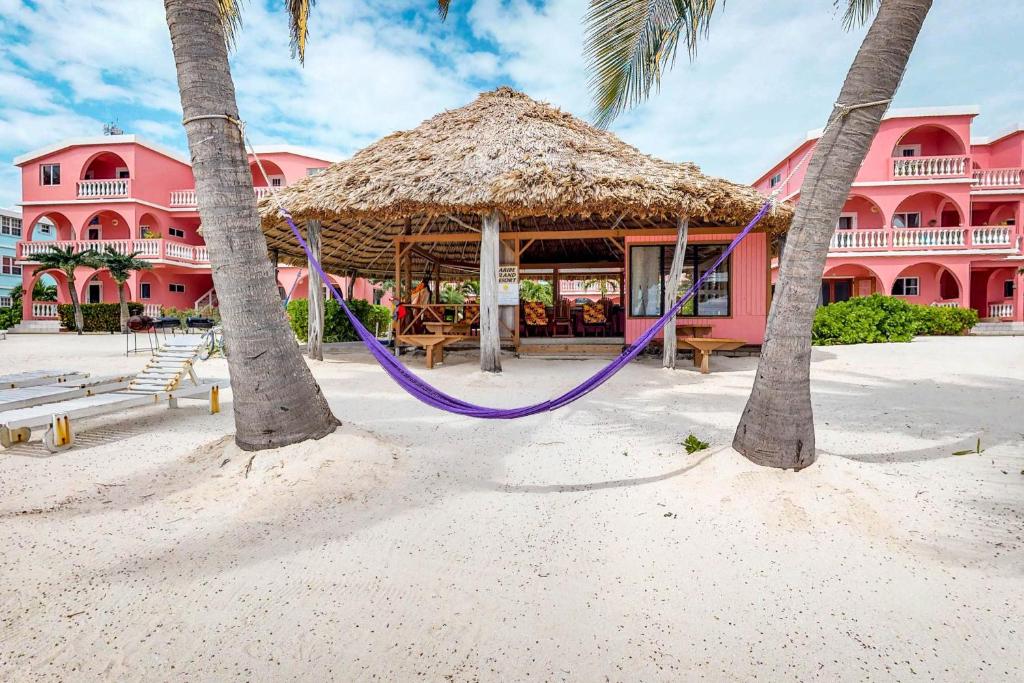 a hammock on the beach in front of a pink building at Seaview - Caribe Island in San Pedro