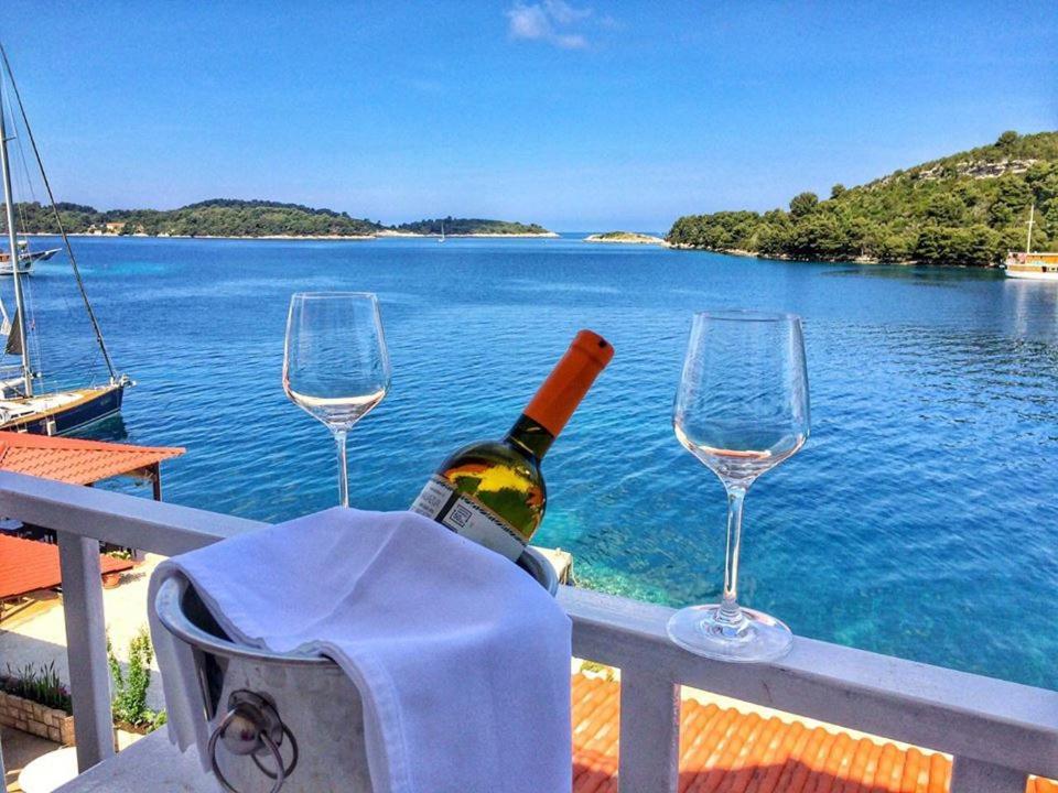 a bottle of wine and two wine glasses on a balcony at Mljet Sunset Apartments in Pomena