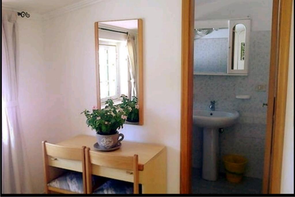 un bagno con lavandino e un tavolo con una pianta di AlmaRé a Palinuro