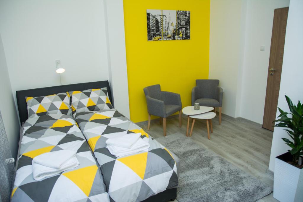 um quarto com uma cama e duas cadeiras e uma parede amarela em Apartment Studio TEO - Near Everywhere You Want to Be em Subotica
