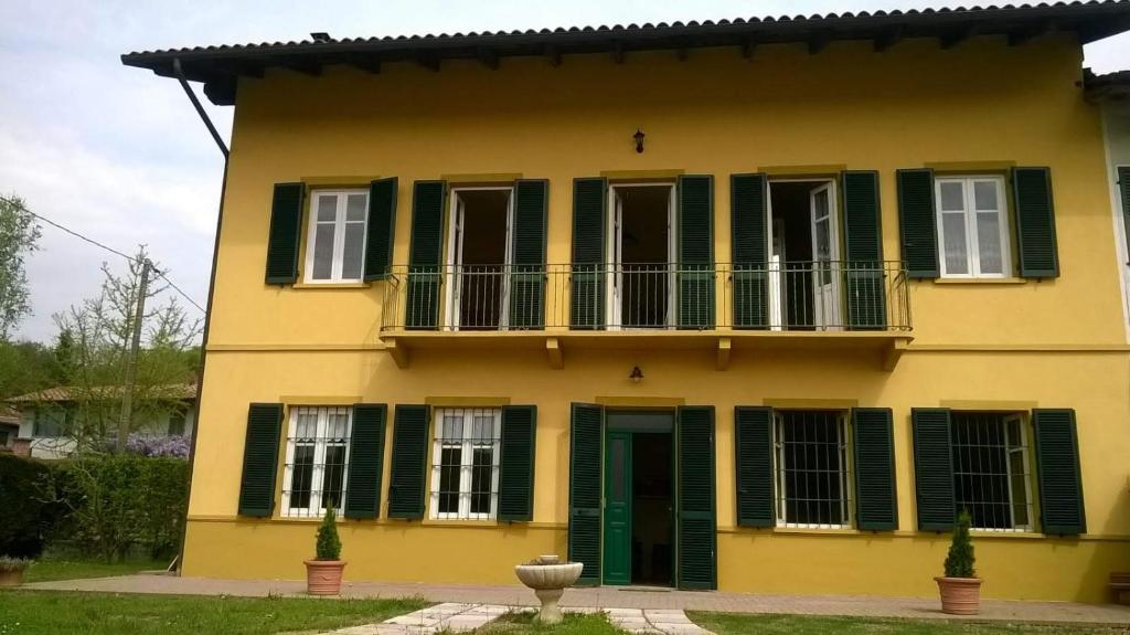 ein gelbes Haus mit grünen Rollläden und einem Balkon in der Unterkunft Casa Virginia / Virginia's Home in Turin - Casalborgone in Casalborgone