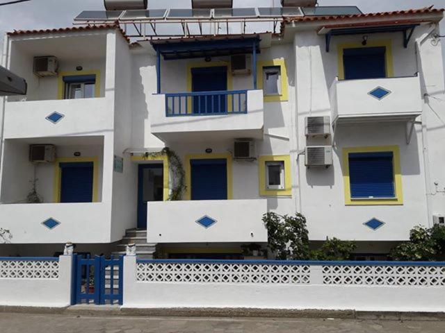 a white building with a blue fence in front of it at Pansion Katerina in Skala Eresou