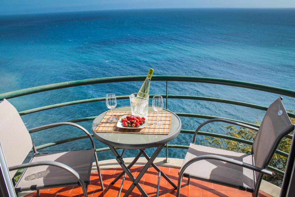 a table with a bottle of wine and a bowl of fruit at The Best Atlantic Ocean View in Câmara de Lobos