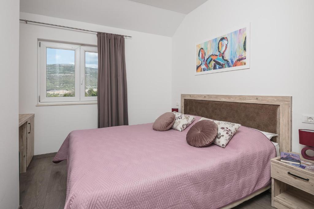 a bedroom with a pink bed with two pillows at Sky Apartments in Čilipi