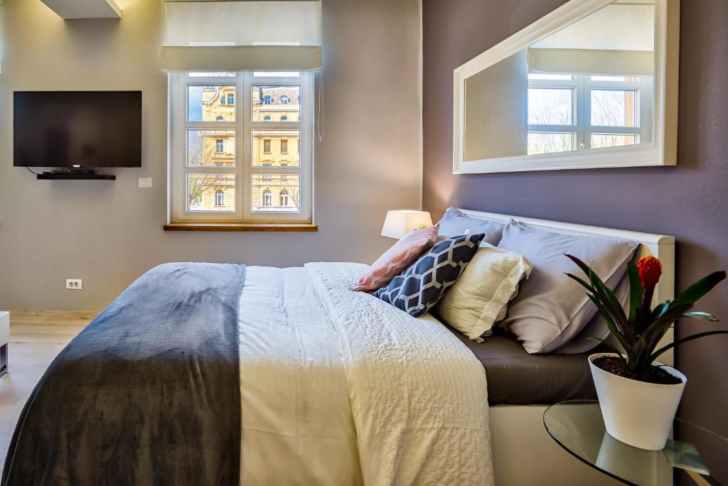 a bedroom with a bed and a tv and two windows at Parkside Apartments in Pula