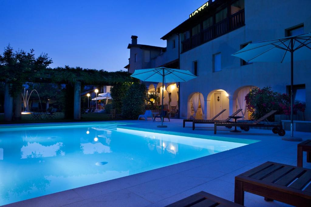 una piscina notturna con ombrelloni di Hotel Villaguarda Landscape Experience a Follina