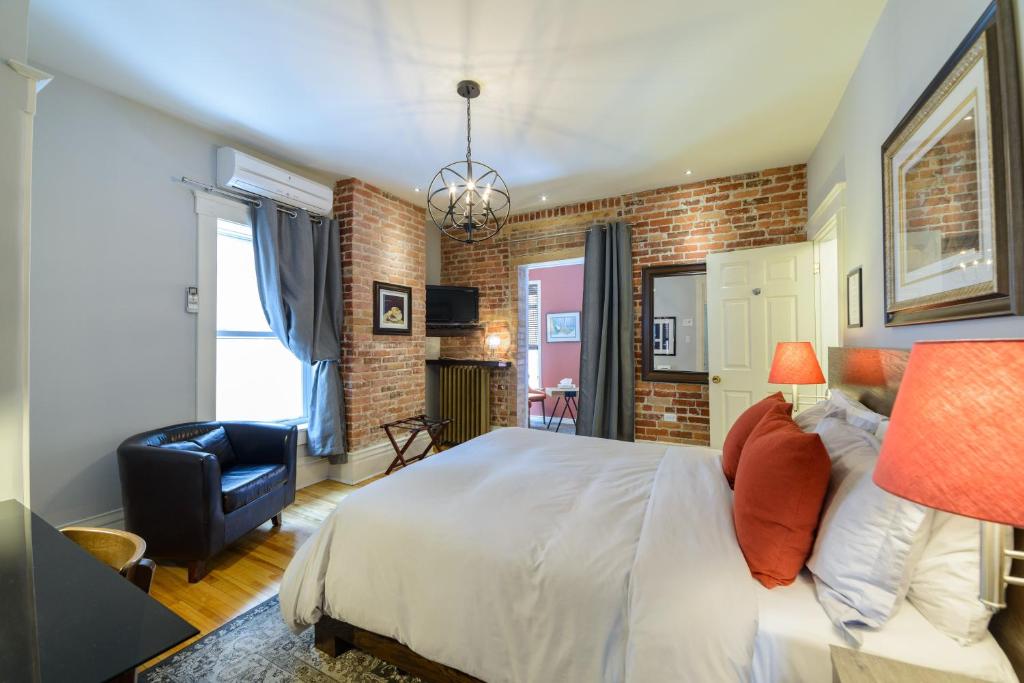 a bedroom with a large white bed and a brick wall at Auberge aux Deux Lions in Quebec City