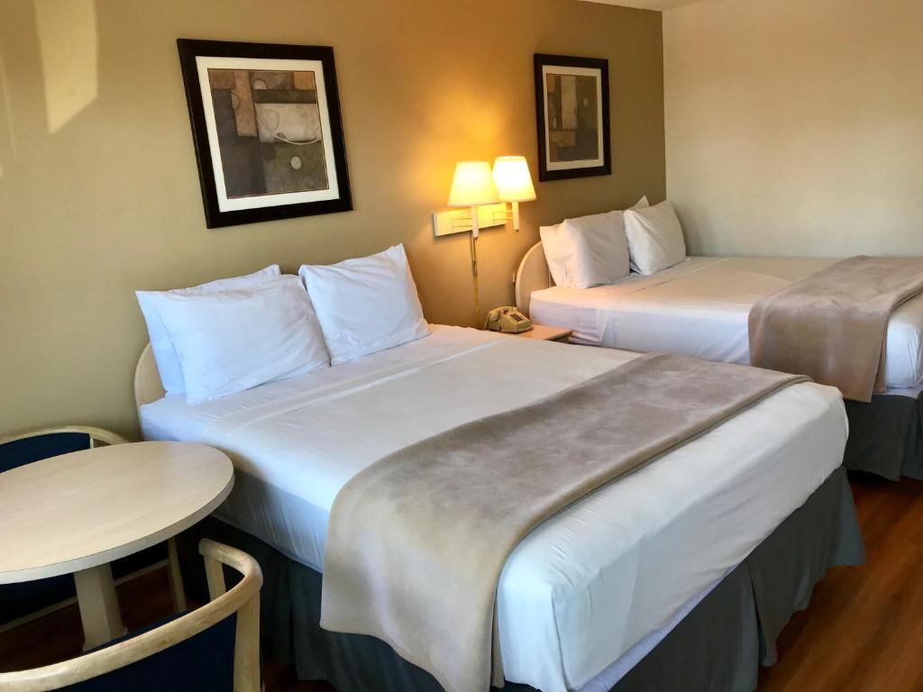 a hotel room with two beds and a table at Sea-Tac Airport Value Inn in SeaTac