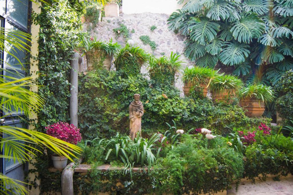 une statue dans un jardin avec des fleurs et des plantes dans l'établissement Las Terrazas, à San Miguel de Allende