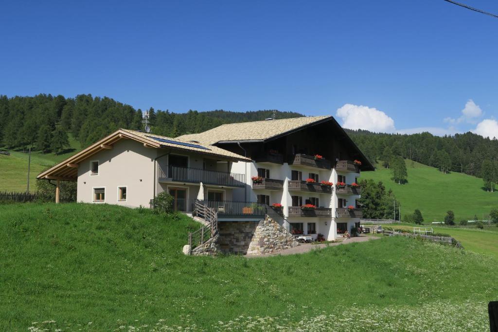 une grande maison blanche sur une colline dans un champ dans l'établissement Residence Scheidnerhof, à Aldino