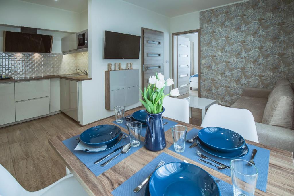 a dining room table with blue plates and utensils at Premium Apartman in Makó