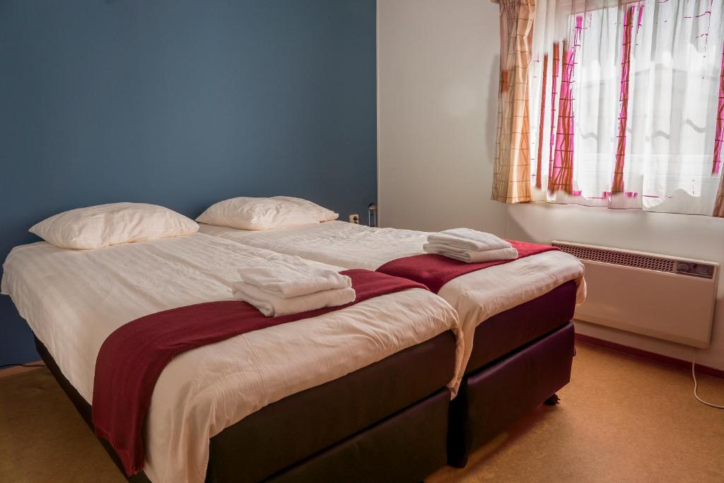 1 dormitorio con 1 cama con toallas en Chaletparc Krabbenkreek Zeeland - Hotel rooms "Terra Mare", en Sint Annaland